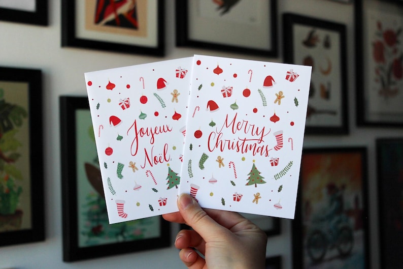 K&ouml;nnte beinhalten: Zwei Weihnachtskarten mit festlichen Designs. Eine Karte sagt "Joyeux Noel" und die andere sagt "Merry Christmas". Beide Karten zeigen rote und gr&uuml;ne Farben, Zuckerstangen und andere Weihnachtsmotive.