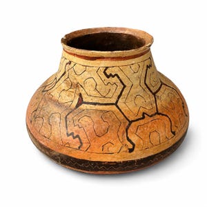 May include: A rounded ceramic pot with a wide opening and a short neck. The exterior features a tan and orange base color decorated with intricate black geometric line patterns and a dark band near the base with a small zigzag border design.