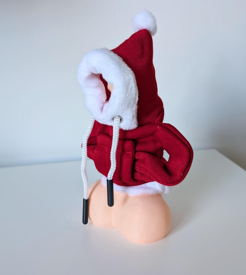 Pu&ograve; includere: Felpa con cappuccio rossa con bordino in pelliccia bianca e coulisse bianca. La felpa &egrave; su una figura color carne.