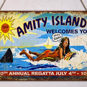 May include: A distressed metal sign reading "Amity Island Welcomes You." The image shows a cartoon of a woman in the sea, a shark fin, and the words "Help!! Shark!" The sign also states "50th Annual Regatta July 4th - 10th."