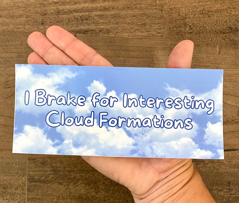 May include: A blue and white bumper sticker with the text "I Brake for Interesting Cloud Formations".