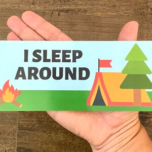 May include: A blue and green camping-themed sticker with the text "I SLEEP AROUND". The sticker features a campfire, a tent with a red flag, and a green pine tree.