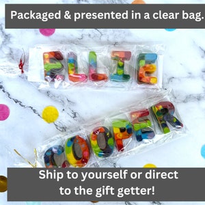 May include: Colorful crayon letters spelling "ELLIE" and "COOPER" packaged in clear bags. The letters are a mix of rainbow colors. The text "Packaged & presented in a clear bag" and "Ship to yourself or direct to the gift getter!" are also visible.