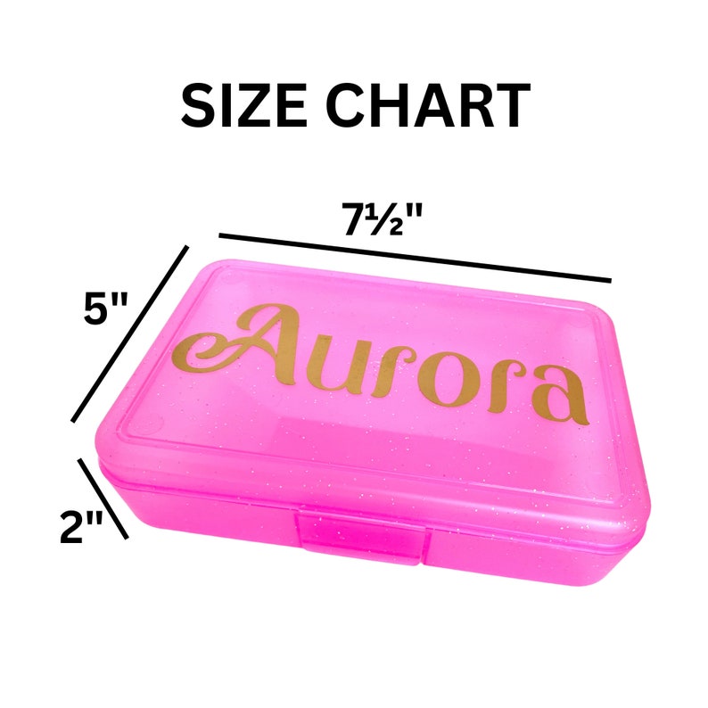 May include: Pink plastic pencil box with a gold glitter finish. The box is 7 1/2 inches long, 5 inches wide, and 2 inches tall. The name "Aurora" is printed in gold on the top of the box.