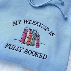 Light blue hoodie with “My Weekend is Fully Booked” embroidery for readers