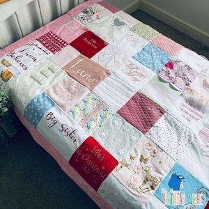May include: A pink and red patchwork quilt with various embroidered names and phrases, including "Luna", "Big Sister", and "Blu's 1st Christmas 2021".