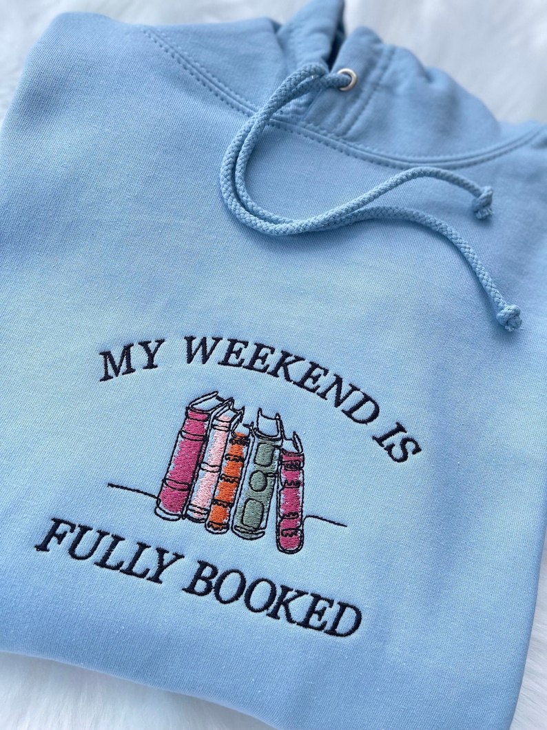 Light blue hoodie with “My Weekend is Fully Booked” embroidery for readers