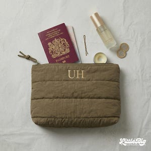 Peut inclure: Une pochette matelassée vert olive avec fermeture éclair et les initiales UH brodées en doré. La pochette est accompagnée d'un passeport britannique bordeaux, d'un flacon pulvérisateur transparent, d'une épingle à cheveux et deux pièces.