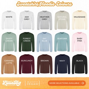 Sweatshirt and hoodie colour chart showing 15 options displayed on long-sleeve tops: White, Ash Grey, Heather Grey, Natural Stone, Milkshake, Dusty Green, Forest Green, Sky Blue, Seafoam, Baby Pink, Caramel Latte, Burgundy, Brown, Navy, and Black.