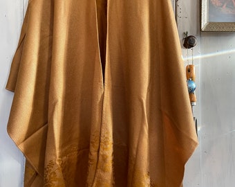 May include: A brown shawl with a subtle floral pattern and fringe trim. The shawl is made of a soft, lightweight fabric and is perfect for layering.
