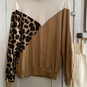 Peut inclure: Un pull à col montant blanc, marron et imprimé léopard à manches longues.