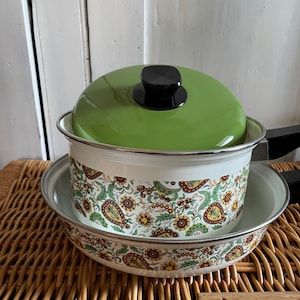 Peut inclure: Un ensemble de deux casseroles en émail vert et blanc avec un motif floral. Les casseroles ont des poignées noires et un bouton noir sur le couvercle.