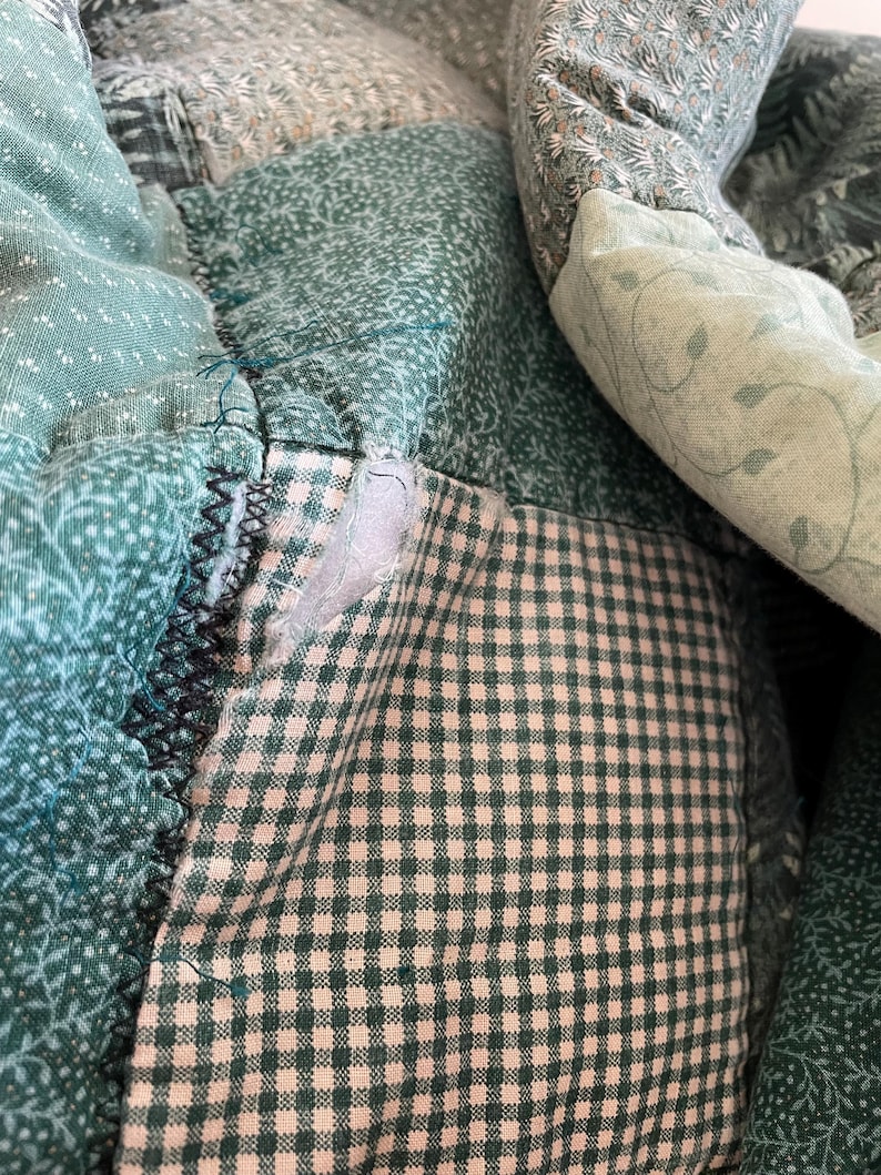 K&ouml;nnte beinhalten: Eine Patchwork-Decke aus gr&uuml;nem und wei&szlig;em Stoff mit einem karierten Muster. Die Decke besteht aus verschiedenen Stoffst&uuml;cken, die zusammengen&auml;ht wurden.