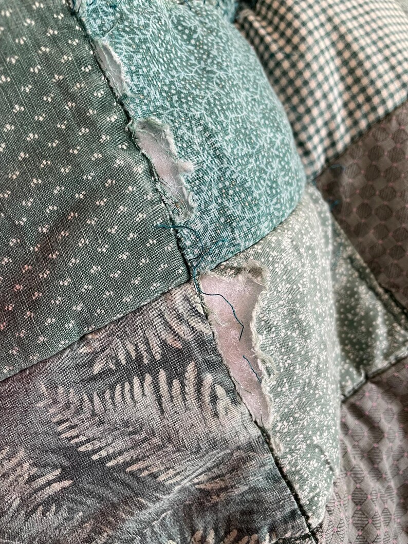 K&ouml;nnte beinhalten: Eine Nahaufnahme einer gr&uuml;n-wei&szlig;en Patchwork-Decke mit ausgefranstem Rand. Die Decke besteht aus verschiedenen Stoffen mit verschiedenen Mustern, darunter Blumen, geometrische Muster und Paisley.