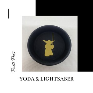 May include: Black ceramic dish with a gold silhouette of Yoda holding a lightsaber. The dish says "YODA & LIGHTSABER" at the bottom.