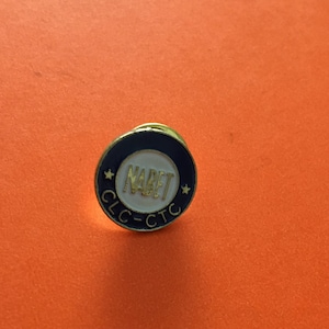 Peut inclure: Une épingle circulaire bleue et dorée avec le texte "CLC-CTC" et "NABET" en blanc.