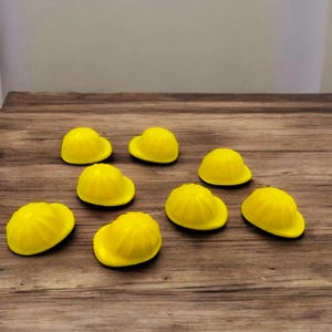 Puede incluir: Ocho favores de fiesta en forma de casco amarillo sobre una superficie de madera.