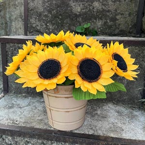 Peut inclure: Un bouquet de tournesols jaune vif avec des centres noirs et des feuilles vertes, dans un seau en m&eacute;tal beige. Les tournesols sont dispos&eacute;s pour cr&eacute;er une pr&eacute;sentation compl&egrave;te et vibrante, id&eacute;ale pour la d&eacute;coration int&eacute;rieure ou les cadeaux.