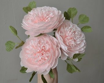 May include: A bouquet of three delicate pink paper flowers with green paper leaves.