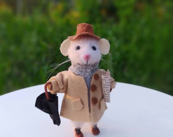 Può includere: Una stravagante statuina di topo in feltro, vestita con un cappotto beige, un cappello marrone e una sciarpa, che tiene un ombrello nero e un giornale arrotolato. Il topo indossa scarpe marroni e ha lunghi baffi bianchi. Il tema generale è un affascinante personaggio in miniatura.