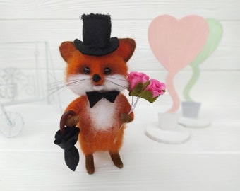 Puede incluir: Un zorro de fieltro con un sombrero de copa negro y una pajarita, sosteniendo un ramo de rosas rosas y un paraguas negro.