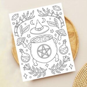 May include: A black and white line drawing of a witch's cauldron with a pentagram inside, surrounded by various magical elements like a witch's hat, mushrooms, crystals, and herbs.