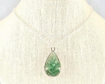 May include: A silver chain necklace with a teardrop-shaped pendant featuring a green gemstone.
