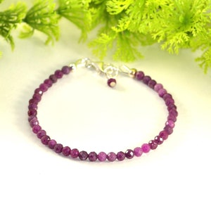 May include: A delicate bracelet made with small, faceted purple gemstones. The bracelet is strung on a silver chain with a small silver clasp.