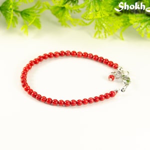 May include: A red coral beaded bracelet with a silver clasp.