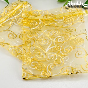 May include: Two gold and white organza gift bags with a swirl pattern. The bags are tied with a gold ribbon.