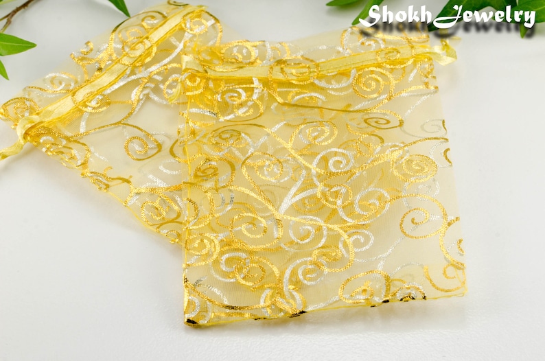 May include: Two gold and white organza gift bags with a swirl pattern. The bags are tied with a gold ribbon.