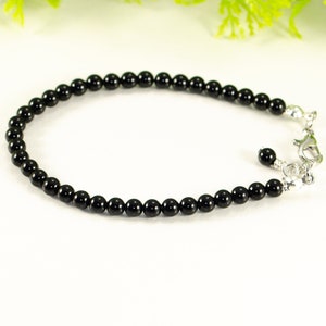 May include: A black onyx beaded bracelet with a silver clasp. The bracelet is made of small, round beads and is approximately 7 inches in length.