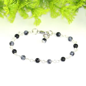 May include: A silver chain bracelet with black and grey snowflake obsidian beads.