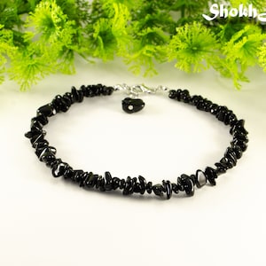 May include: Black gemstone chip bracelet with a silver clasp and a small black gemstone charm.
