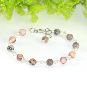May include: A silver chain bracelet with pink and grey gemstone beads.