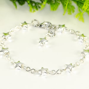 May include: A silver chain bracelet with star-shaped charms. The bracelet has a lobster clasp closure.