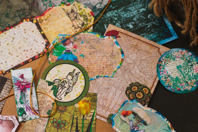 May include: Assortment of decorative paper ephemera with whimsical fairy and floral designs. The paper ephemera is in shades of green, blue, brown, and white.