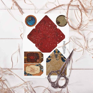May include: Printable set of four paper crafts featuring a scorpion design. The set includes a red envelope with gold stars, a round tag with a blue scorpion, and two rectangular tags with a brown scorpion.