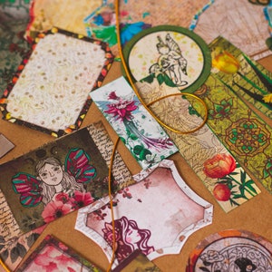 May include: Assortment of decorative paper ephemera with floral, fairy, and nature-inspired designs. The papers are in shades of green, brown, pink, and white.