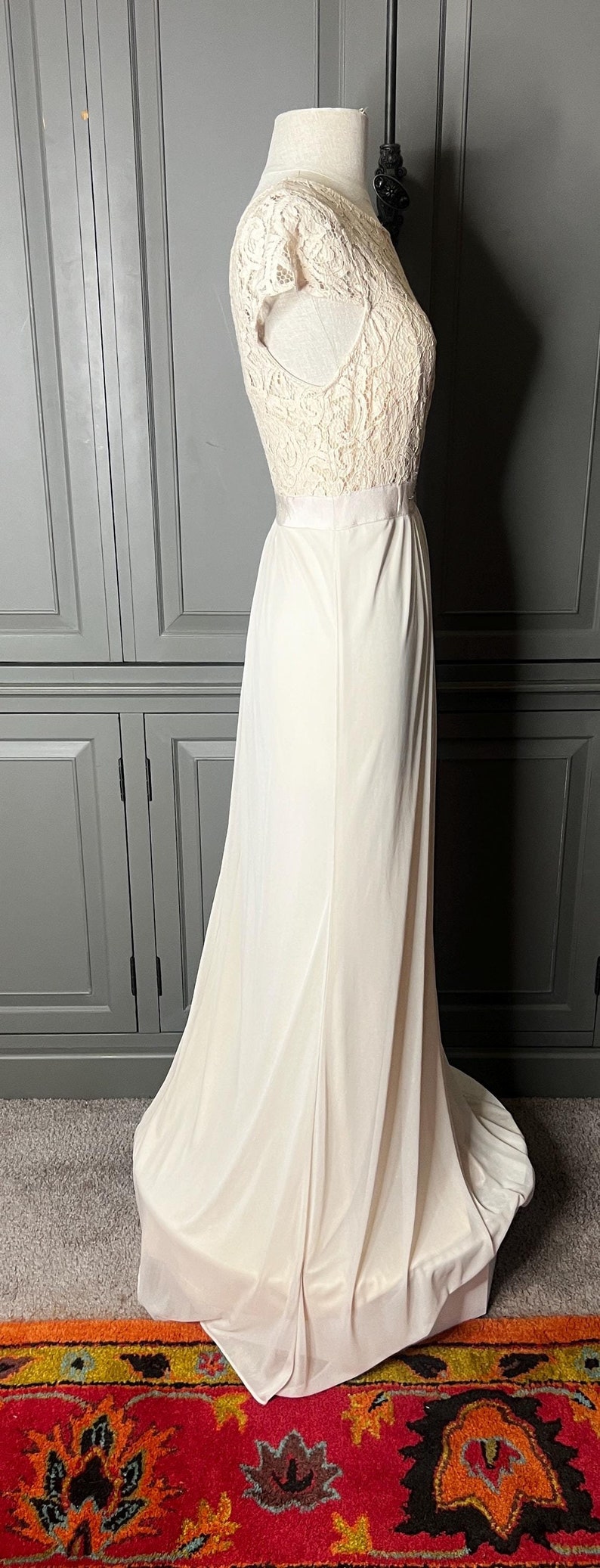 Op de afbeelding: Een wit kant topje met een witte rok. De rok is lang en zwierig. Het topje heeft korte mouwen en een ronde hals. De outfit is op een wit mannequin.