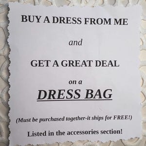 May include: A white paper sign with the text "BUY A DRESS FROM ME and GET A GREAT DEAL on a DRESS BAG". The sign has a decorative edge and is on a white, textured surface.
