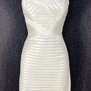 May include: White, bodycon dress with a structured bodice and a fitted skirt. The dress features a scoop neckline, thick straps, and horizontal ribbing throughout the design. The dress is displayed on a mannequin.