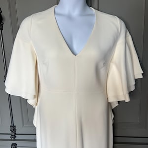 May include: A white maxi dress with a V-neck and ruffled sleeves.