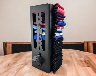 May include: A black metal beer bottle opener with a built-in holder for bottle caps. The holder is filled with a stack of colorful bottle caps.