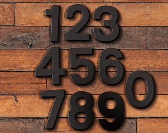 May include: Black numbers 1 through 9 and 0 on a wooden background.