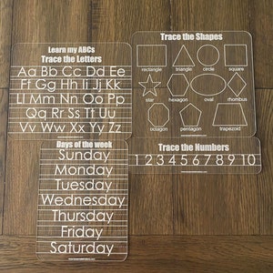 Op de afbeelding: Een set van vier transparante acryl traceerborden voor vroeg leren. Bevat borden voor het traceren van letters, vormen, cijfers en dagen van de week. Elk bord heeft witte tekst en contouren om te traceren. De set is gelabeld met "Bundle 3".