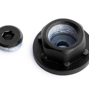 May include: A black metal nut with a hexagonal shape and a threaded hole in the center. The nut is attached to a black metal washer with six small holes around the edge.
