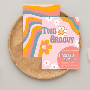 Pode incluir: Convite de aniversário "Two Groovy" com um design retrô. O convite apresenta um fundo rosa com flores de margarida e o texto "Two Groovy". O convite inclui o nome "Hadley's" e os detalhes do evento.