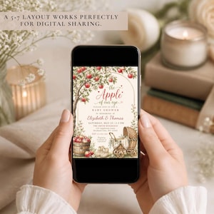 May include: A smartphone displaying a digital baby shower invitation with an apple tree illustration, a basket of red apples, and a vintage baby carriage. The text reads: The Apple of our eye, Please join us for a baby shower to honouring Elizabeth & Thomas.