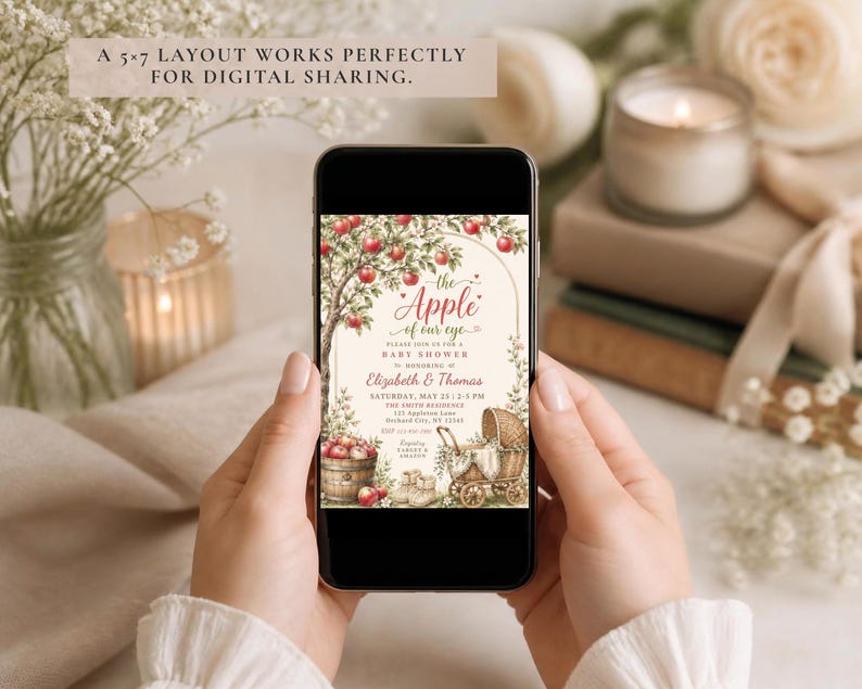 May include: A smartphone displaying a digital baby shower invitation with an apple tree illustration, a basket of red apples, and a vintage baby carriage. The text reads: The Apple of our eye, Please join us for a baby shower to honouring Elizabeth & Thomas.